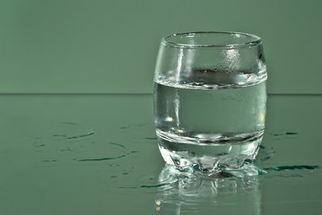 Alcoholic drink in clear glasses. Little cups isolated on green background. Frozen drinks on glass table.