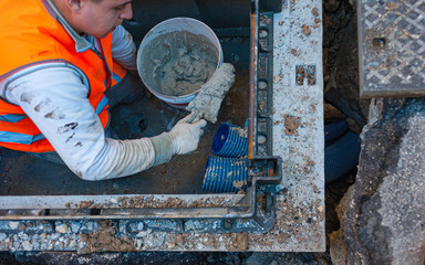 construction worker is repairing a pit of the data transmission line with optical fibers, sealing the pipe with cement mortar