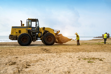 Obraz premium Bulldozers clean up trash on the beach