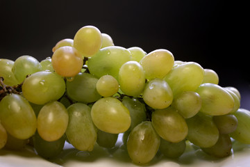 Bunch of green grape isolated on a plate on a black background