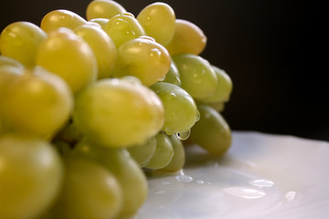 Bunch of green grape isolated on a plate on a black background