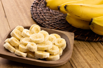banana slices in rustic pot with bunch of bananas in the background