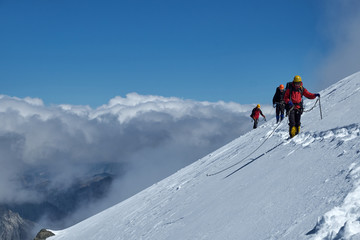Bunch of mountaineers climbs or alpinists to the top of a snow-capped mountain