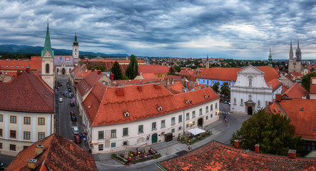 Panoramic view of Zagreb Old city from Lotrscak tower. Scenic cityscape of Upper town (Gornij Grad or Gradec) with historical medieval buildings, churches, streets and dramatic cloudy sky, Croatia
