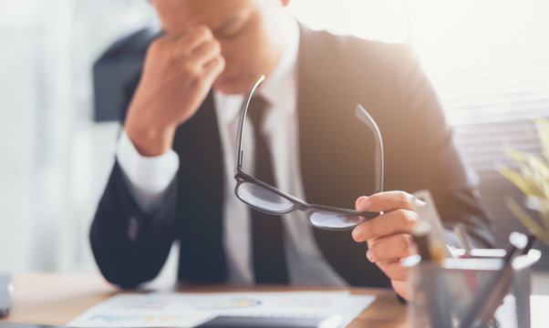 Businessman In Black Suit Of Hands Touching On The Eyes Due To Tiredness From Working Computer For A Long Time, May Be The Cause Of Office Syndrome.