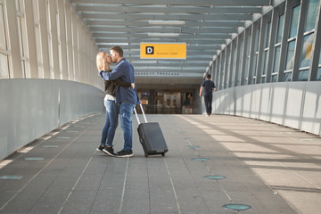 Side photo of cuddling man and woman at airport