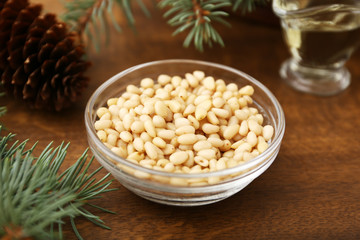Cedar pine nuts in glass bowls with cones, cedar brunch on wooden background.