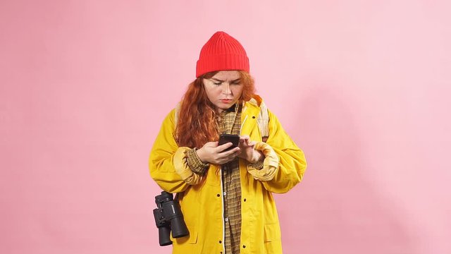 Charming red-haired girl tourist looking in the mobile Navigator the way to the destination