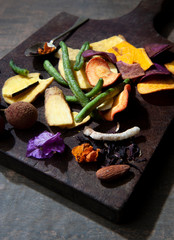 Chopping board, dark background with cereals, dehydrated carrots, beets, string beans.Fruit grape, cinnamon, almond.Half jute background. Close view.