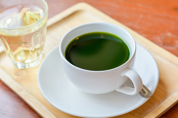 Set of hot matcha (green tea) in white ceramic cup served on wooden tray on table in cafe and coffee shop. Healty beverages of japan for reduce sugar in blood.