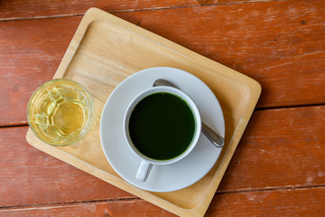 Set of hot matcha (green tea) in white ceramic cup served on wooden tray on table in cafe and coffee shop. Healty beverages of japan for reduce sugar in blood.