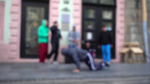 Unknown guys dance break on the street of the city. Slow motion. Out of focus.