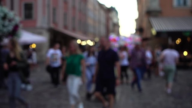 Crowds of people walk through the streets of the city. Out of focus. Slow motion.