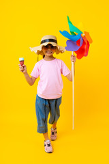 Portrait of young Asian pretty girl walking and  holding colorful turbine and ice cream,Thai kid in summer style on yellow background