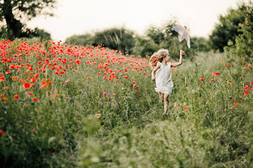 a girl runs with a toy among the poppy field