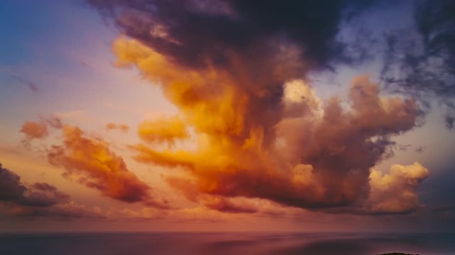 wonderful thick orange and grey clouds lit by setting sunlight float in endless blue sky over ocean in summer evening time lapse. Concept travel tourism tropical nature landscape sunset. Thailand 4K