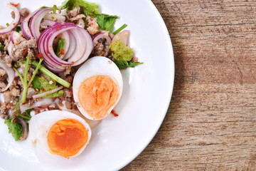 boiled egg half cutting topping sour and spicy minced pork salad on plate