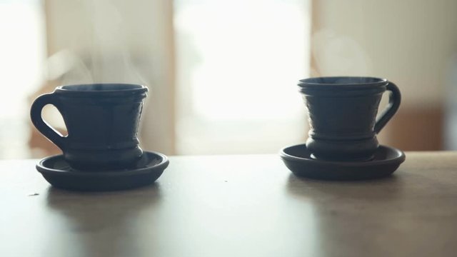 Waiter bringing a fresh maiden coffee in black clay cup and putting on table close up view. Coffee consummation in modern coffee shop concept cinematic Slow motion footage.
