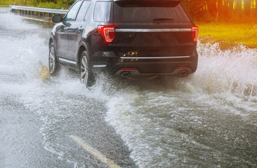 cars driving on a flooded road during a flood caused by heavy rain,