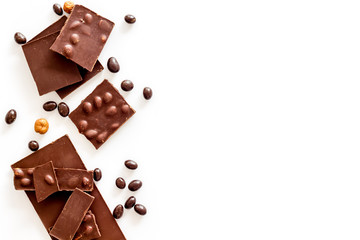 Chocolate with nuts and its ingredients on white background top view copyspace