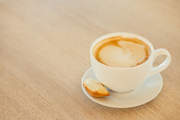 Cup of coffee with biscuit for breakfast on a wooden table. .