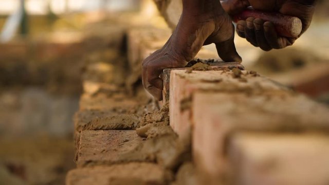 Blue collar workers laying bricks for a home.