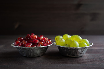 grapes and pomegranate in a plate on a dark background