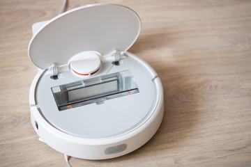 Open robotic wireless smart vacuum cleaner working on laminate flooring