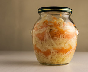 Fermented cabbage with carrots in a glass jar, close-up