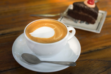 Hot coffee cup on plate with chocolate cake.