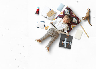 Little boy sits and plays on the floor among his toys