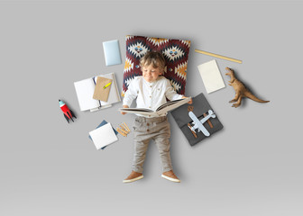 Little boy sits and plays on the floor among his toys