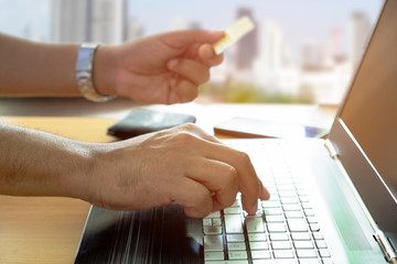 Fototapeta premium Young man holding credit card shopping online with using laptop at home. Indoor.
