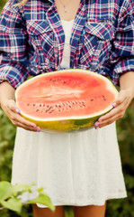 Woman with a piece of ripe watermelon in a hand in a picnic. Autumn harvest. Autumn concept