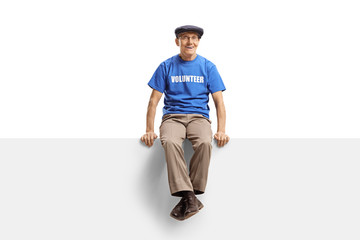 Elderly male volunteer sitting on blank white panel
