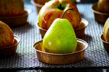Green pear in a paper plate on the background of apples