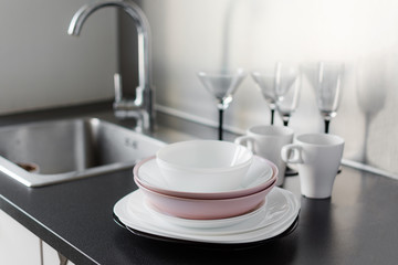 Set of fresh washed plates and cutlery on the kitchen table.