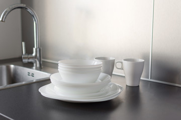 Set of fresh washed plates and cutlery on the kitchen table.