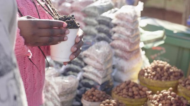 Close up shot of a woman&rsquo;s hand holding a cup of edible African caterpillars.