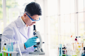 Asian man scientist working in a lab with microscope