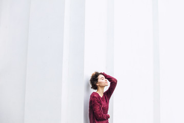 Young beautiful adult girl with natural makeup fashionable and happy on white building wall background