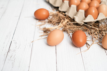 Top view brown chicken egg  in carton box on the hay with white wooden background, Flat lay with copy space