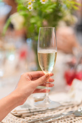Woman hand holding a glass of champagne with blurred party background.