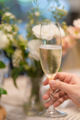 Woman hand holding a glass of champagne with blurred party background.