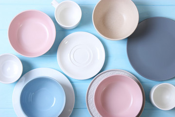 Set of dishes and kitchen utensils on a colored background top view.