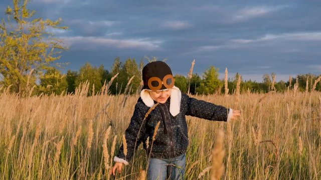 Happy kid playing with toy airplane against autumn sky background at sunset