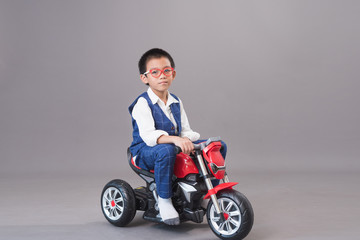Happy  Asian boys ride motorcycle on gray background.
