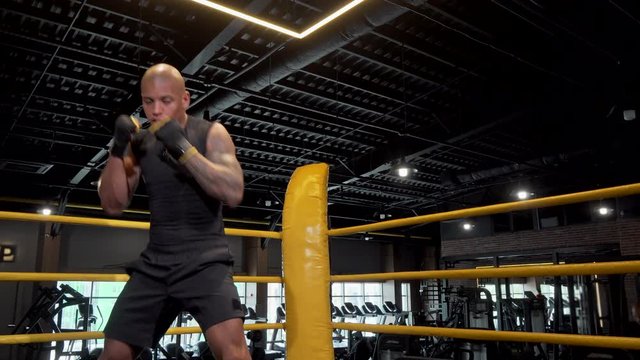 African male boxing fighter shadow boxing at the gym. Handsome boxer practicing at sports club. Male fighter shadowboxing in boxing ring. Determination, workout concept