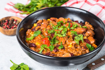 Chili con carne from meat and vegetables on stone table close up.