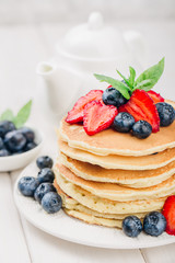 Classic american pancakes with fresh berry on white wood background. Summer homemade breakfast.